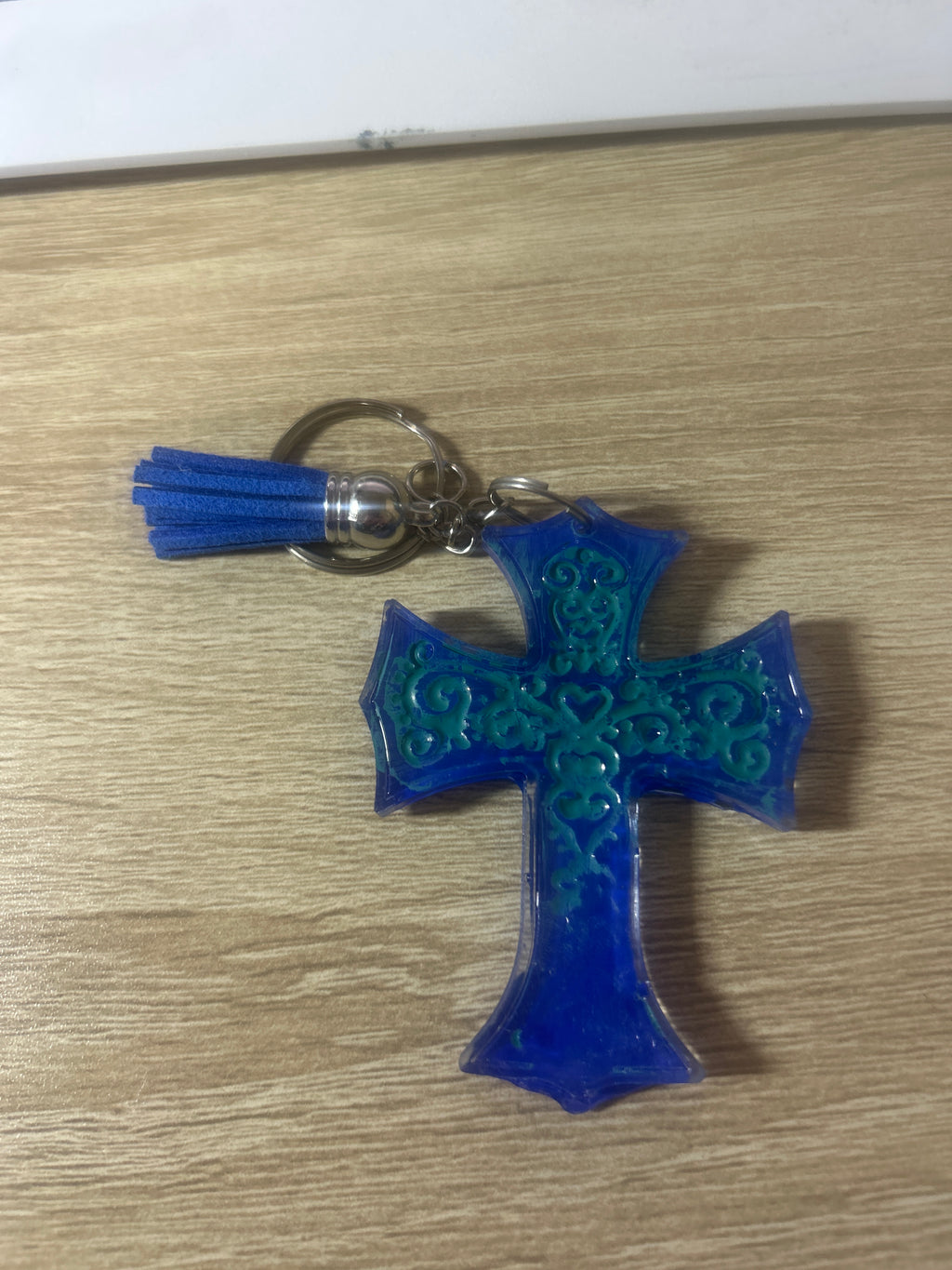 Royal blue resin cross keychain with teal filigree detailing, blue tassel and silver ring