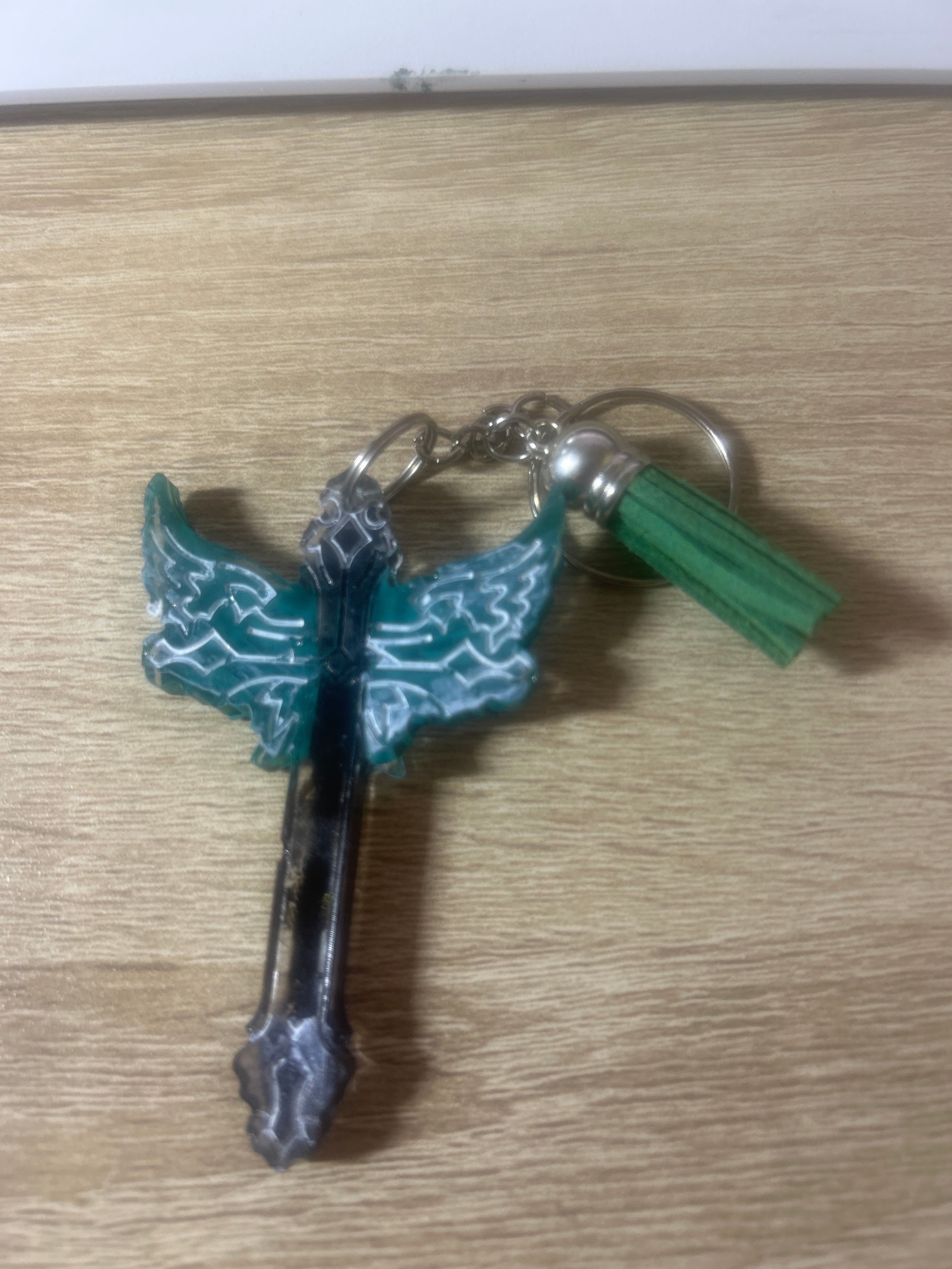 Teal blue butterfly wing resin cross keychain with green tassel and silver ring